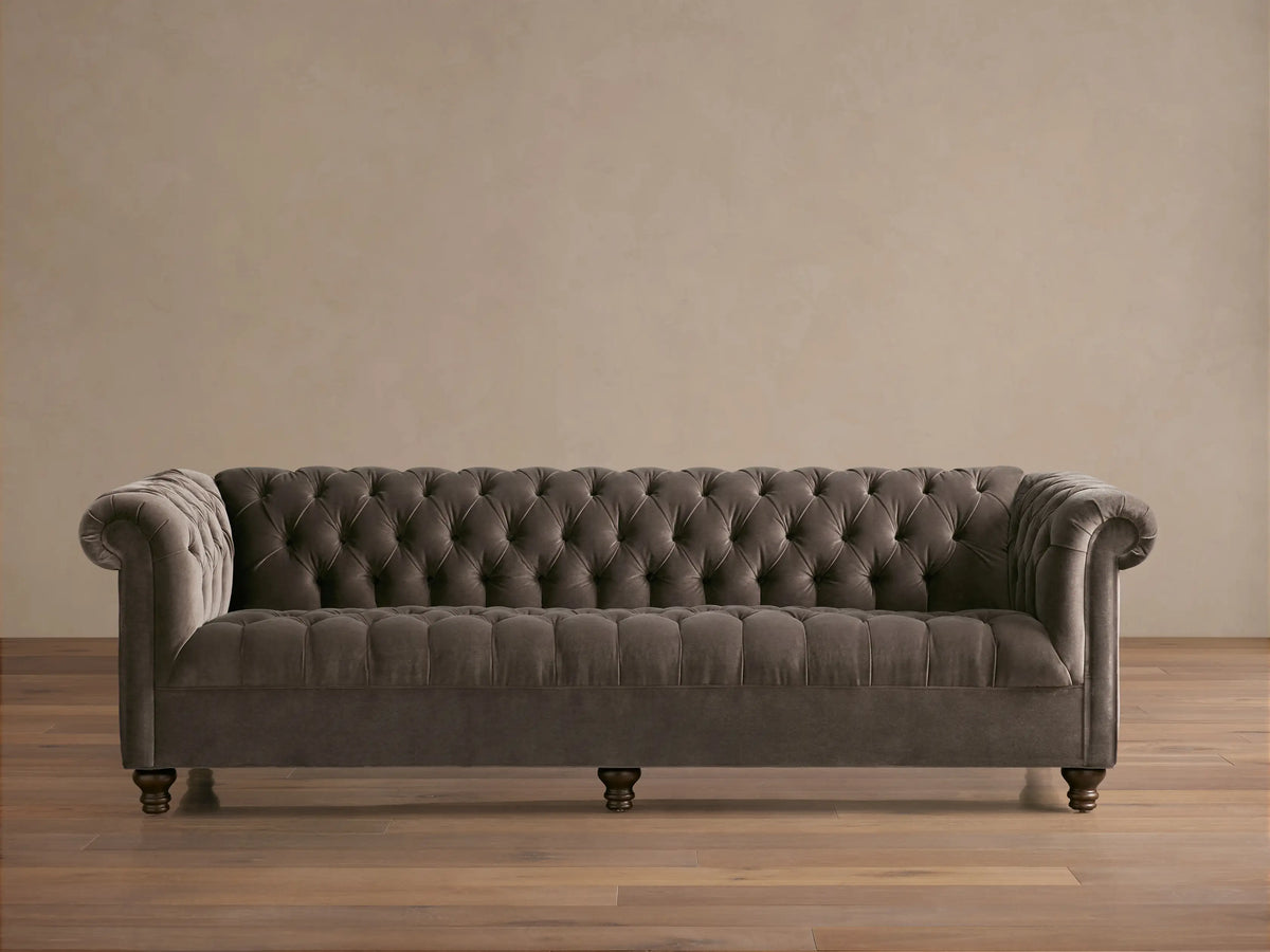 Berwick Sofa: Tufted mink velvet Chesterfield sofa with rolled arms and dark turned legs, against a neutral wall.