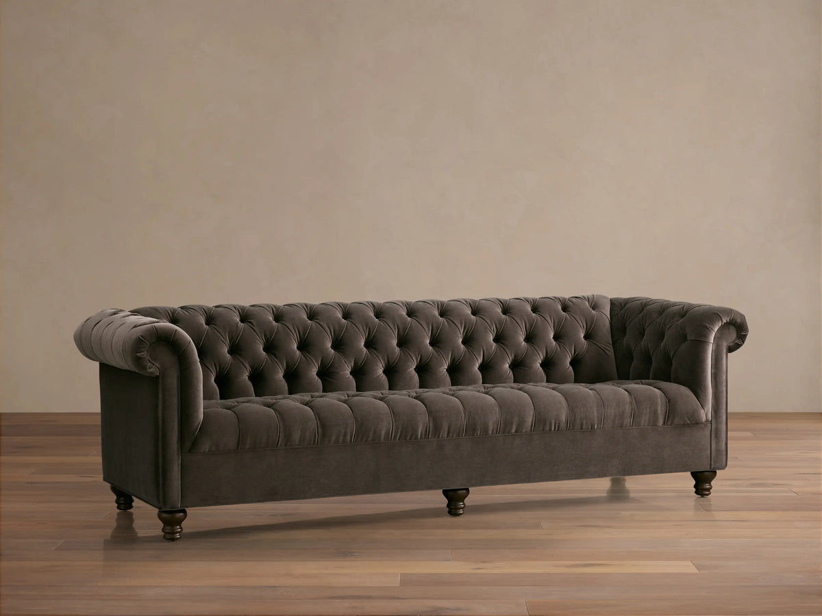 Berwick Sofa: Tufted mink velvet Chesterfield sofa with rolled arms and dark turned legs, against a neutral wall.