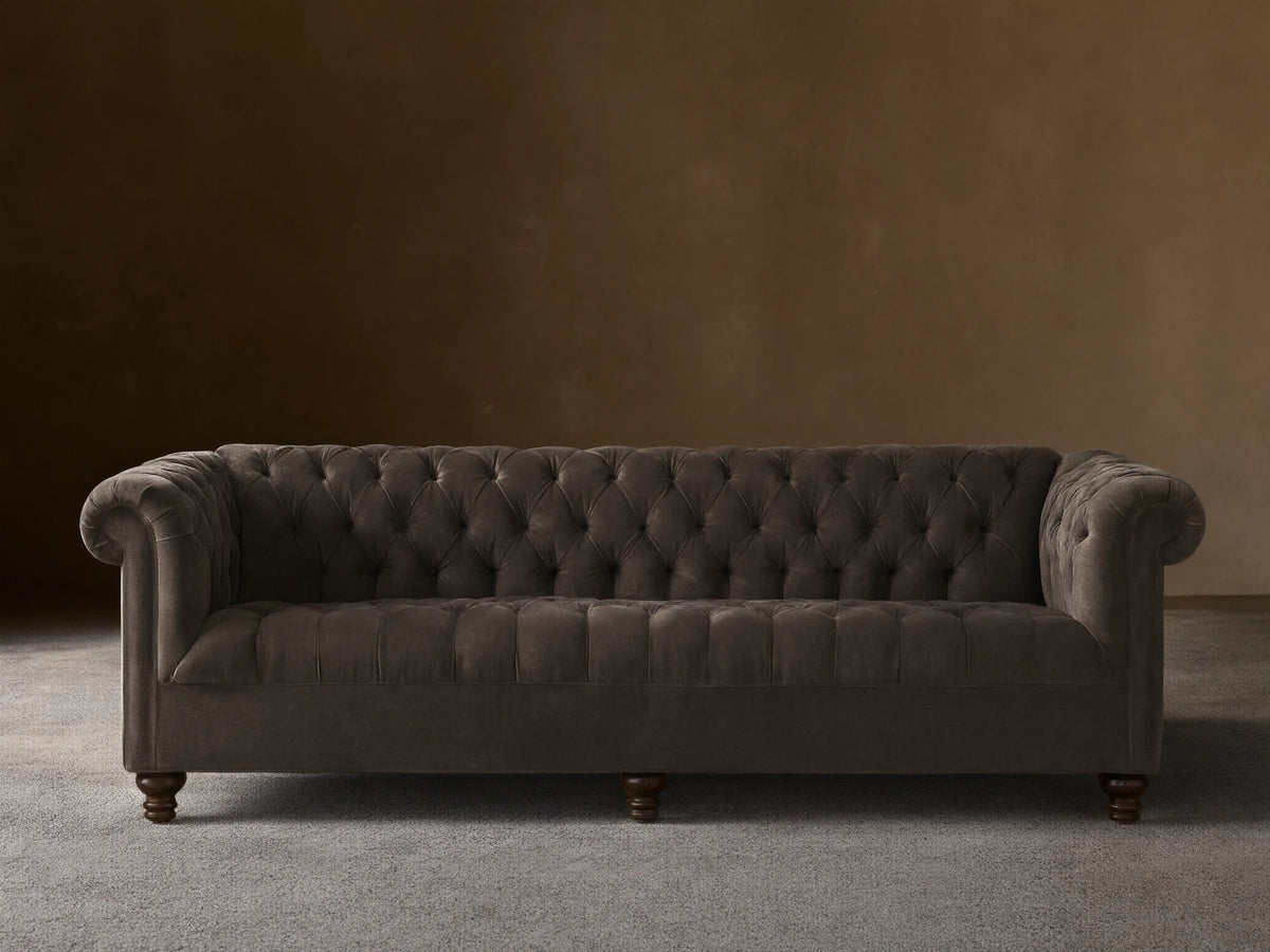 Berwick Sofa: Tufted mink velvet Chesterfield sofa with rolled arms and dark turned legs, against a neutral wall.