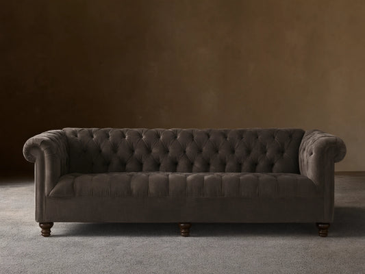 Berwick Sofa: Tufted mink velvet Chesterfield sofa with rolled arms and dark turned legs, against a neutral wall.