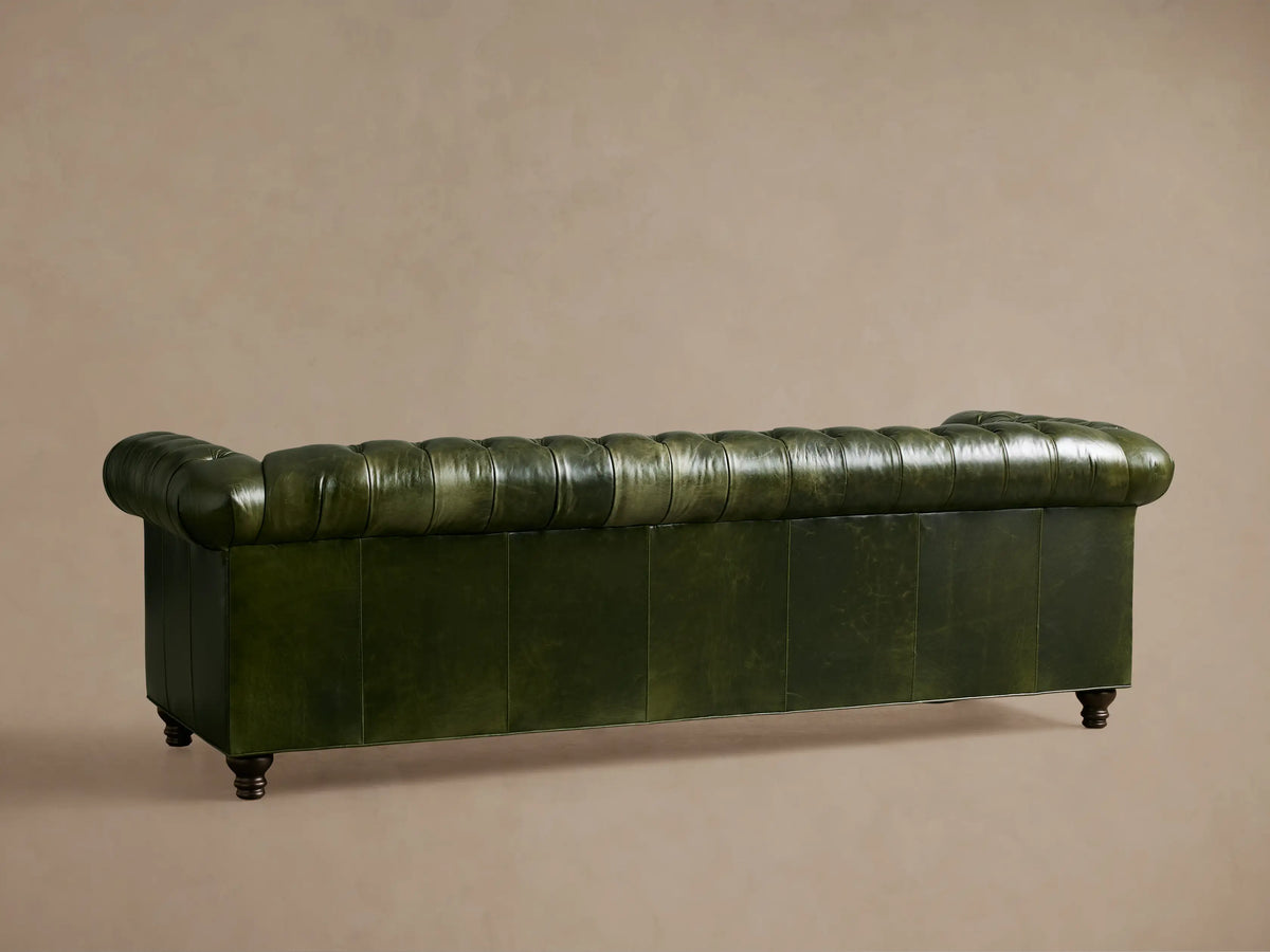 Berwick Leather Sofa, deep green tufted leather with classic rolled arm, showing dark carved leg.