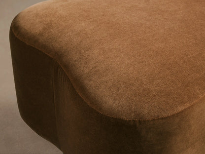 Close-up of the rich brown Barbey Ottoman, featuring its soft, textured upholstery and gently curved, rounded shape.