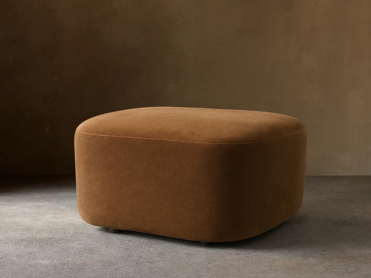Front view of a brown velvet upholstered Barbey Ottoman with a rounded, organic shape.