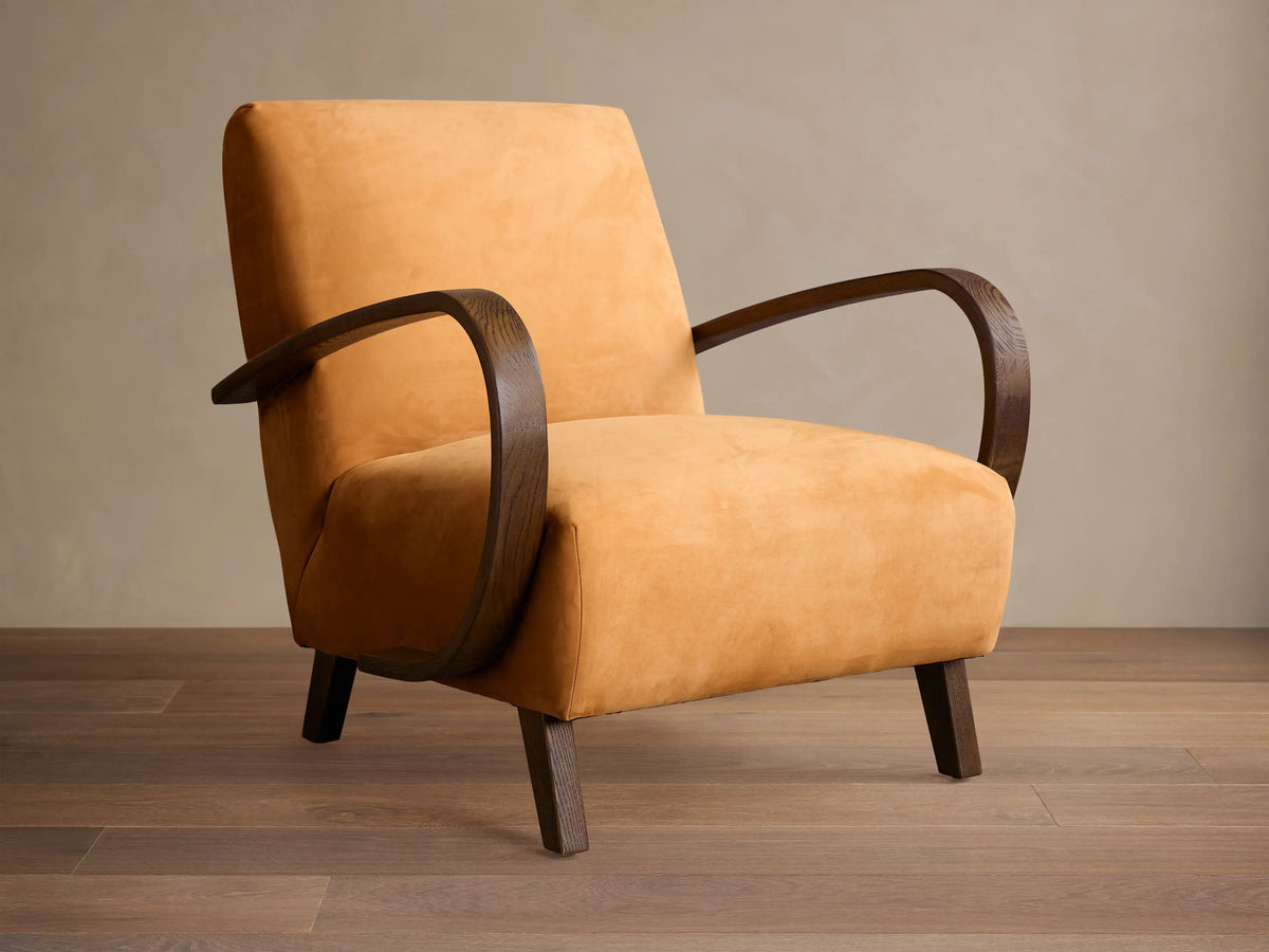 Ochre Gabel leather armchair with dark curved wood armrests and legs, angled right on a wooden floor.