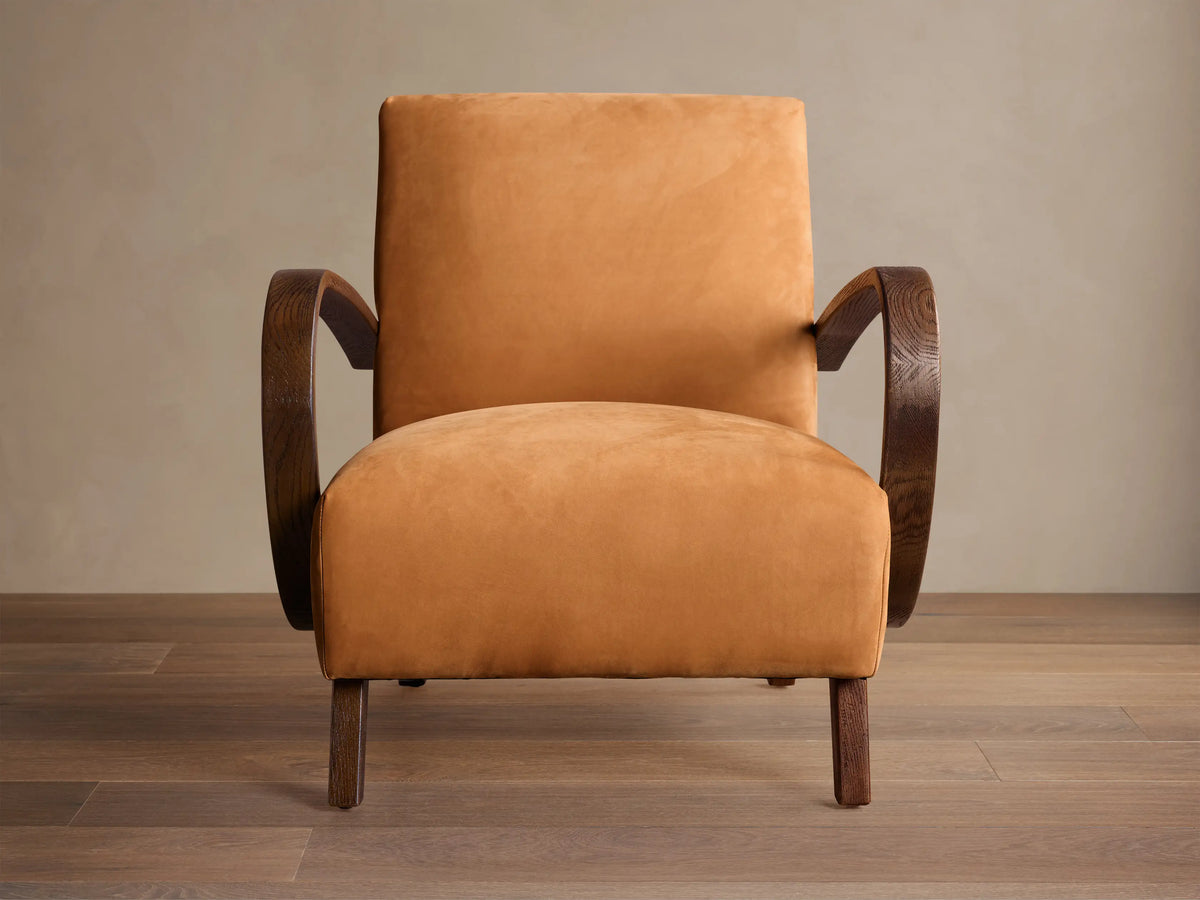 Ochre Gabel leather armchair with dark curved wood armrests and legs, angled right on a wooden floor.