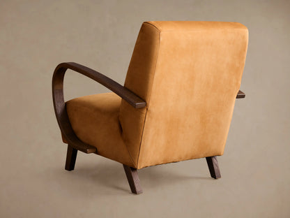 Angled close-up of a Gabel Leather Chair, showcasing its camel-colored leather upholstery and dark wood curved armrests.