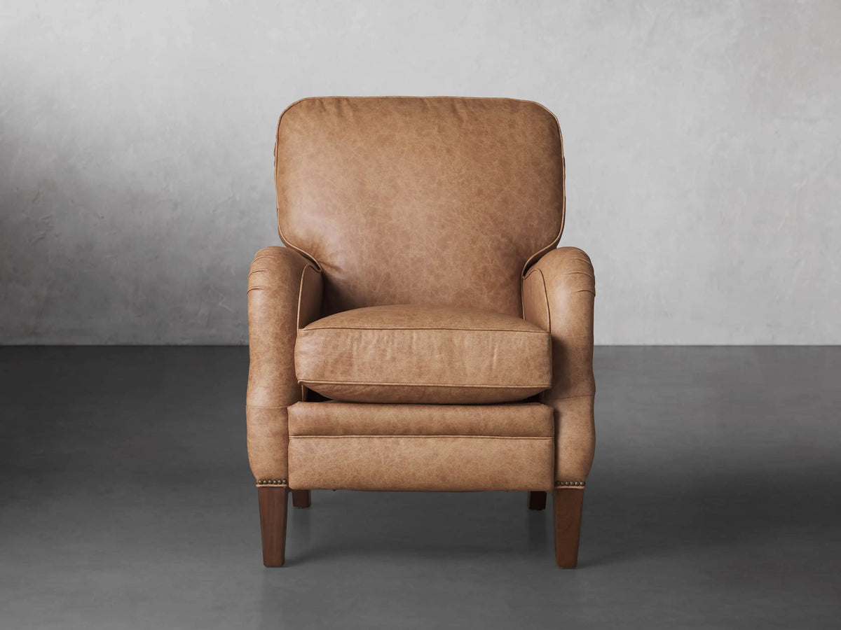 Brooklyn Leather Recliner in warm tan. Front view, slightly angled, showing soft, textured leather, rolled arms, and tapered wooden legs.