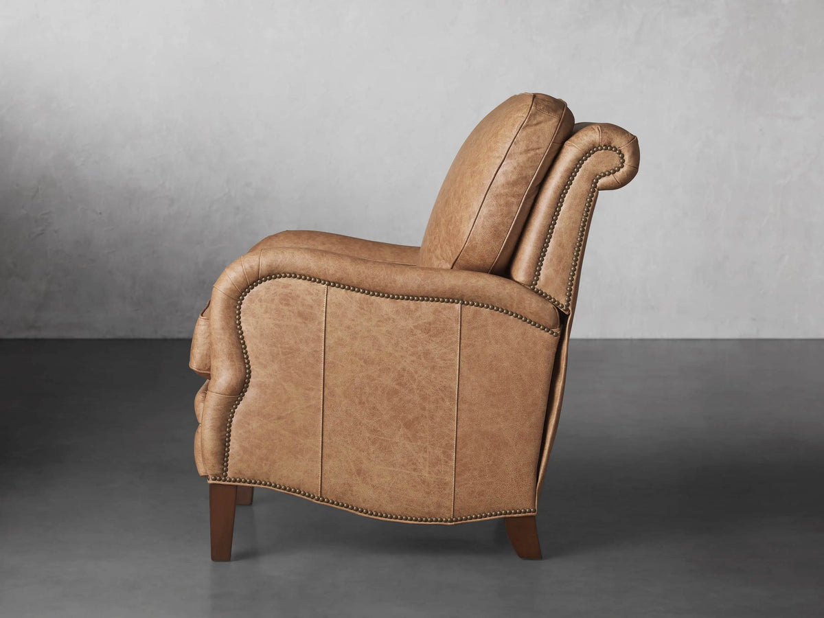Close-up of a Brooklyn Leather Recliner armrest and seat in distressed light brown leather with decorative nailhead trim.