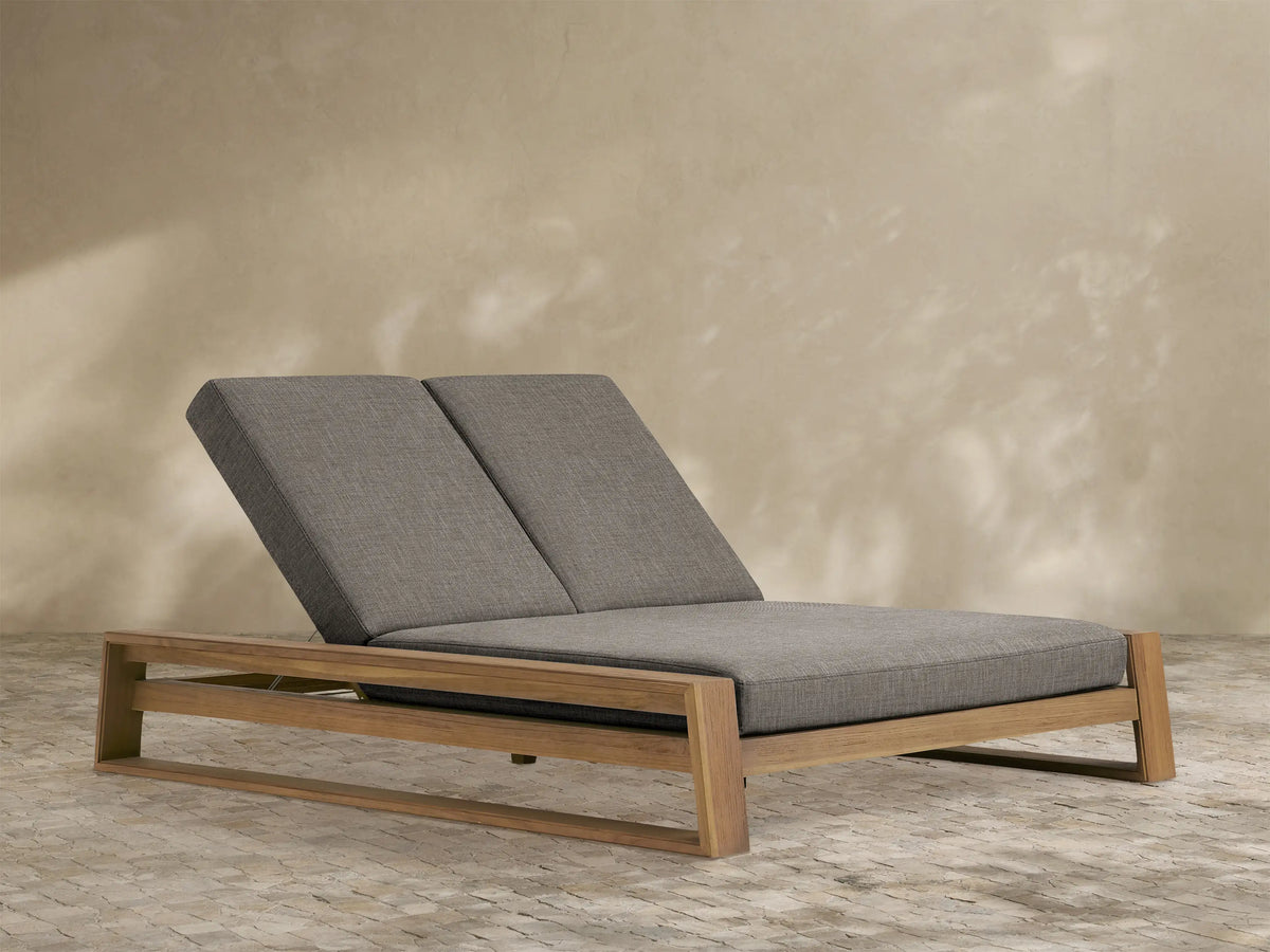 Canyon Outdoor Teak Double Chaise with natural teak wood frame and two grey cushioned sections, both with raised backrests.