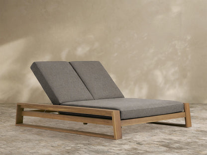 Canyon Outdoor Teak Double Chaise with natural teak wood frame and two grey cushioned sections, both with raised backrests.