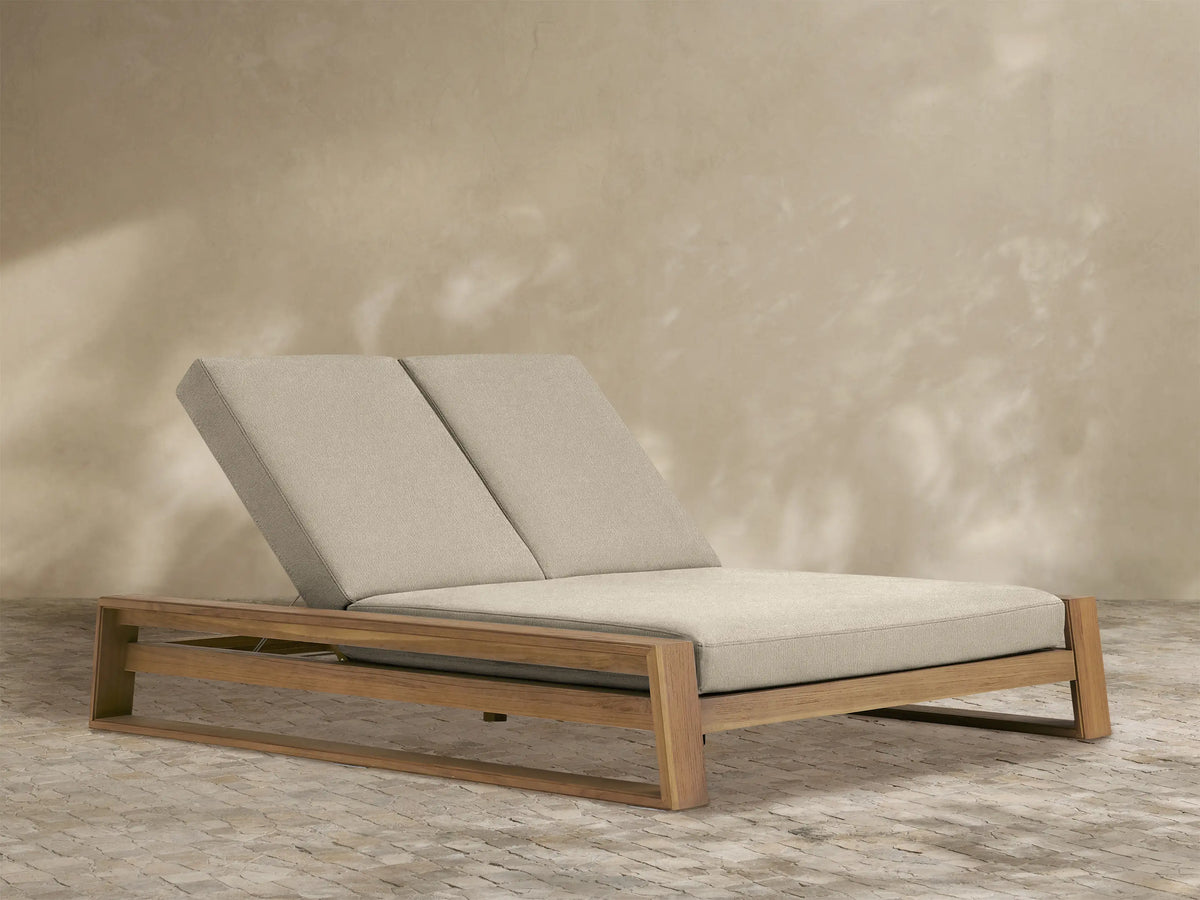 Canyon Outdoor Teak Double Chaise with two tan cushioned seats & backs, reclined upwards, on a light brown teak frame.