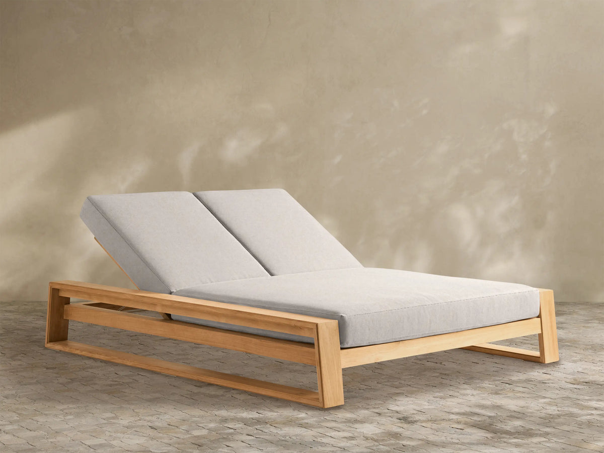 Angled view of a Canyon Teak Double Chaise with a light brown wood frame and two separate light beige adjustable cushions.