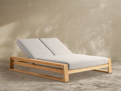 Angled view of a Canyon Teak Double Chaise with a light brown wood frame and two separate light beige adjustable cushions.
