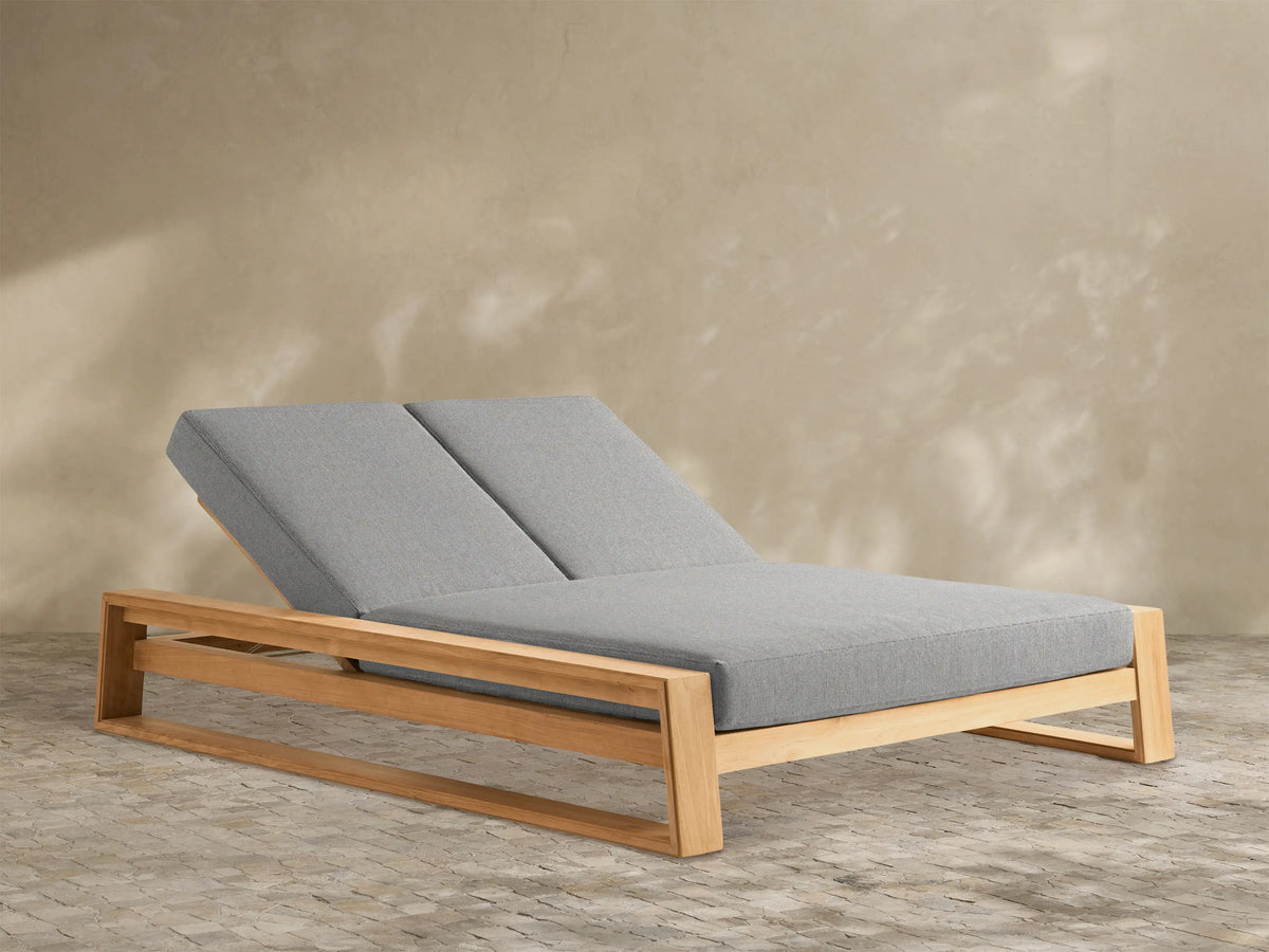 Canyon Outdoor Teak Double Chaise with a light wooden frame and two gray cushions. Backrests are individually elevated.