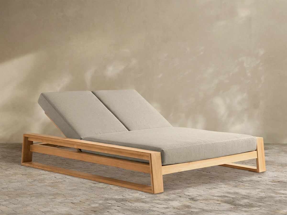 Canyon Outdoor Teak Double Chaise with light natural teak frame and two light beige adjustable cushions, angled on white background.