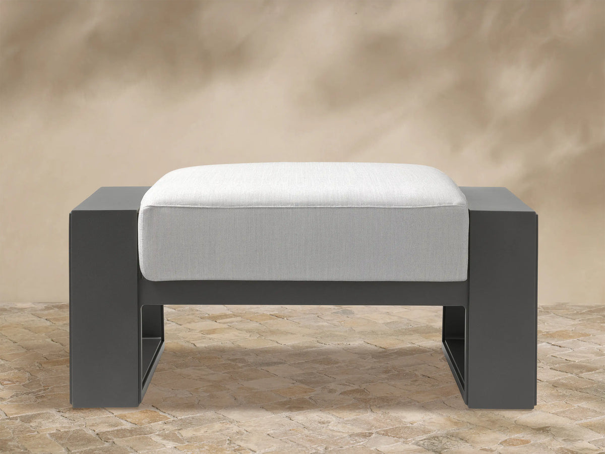Front view: Canyon Outdoor Aluminum Ottoman with a dark gray rectangular frame and thick, light gray cushion on top.