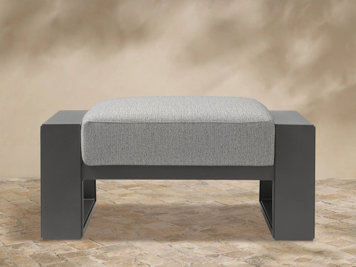Canyon Outdoor Aluminum Ottoman. Front view of a dark grey aluminum frame with a light grey textured cushion on top.