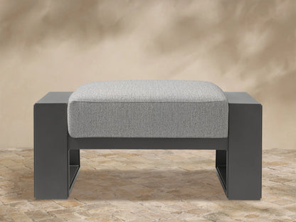 Canyon Outdoor Aluminum Ottoman. Front view of a dark grey aluminum frame with a light grey textured cushion on top.