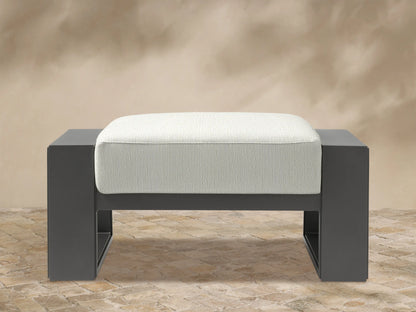 Canyon Outdoor Aluminum Ottoman with a dark gray frame and a light beige, textured fabric cushion, front view.