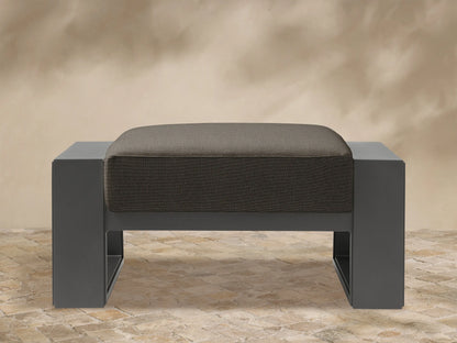 Front view of Canyon Outdoor Aluminum Ottoman. Dark charcoal aluminum frame supports a thick, textured gray-brown cushion.