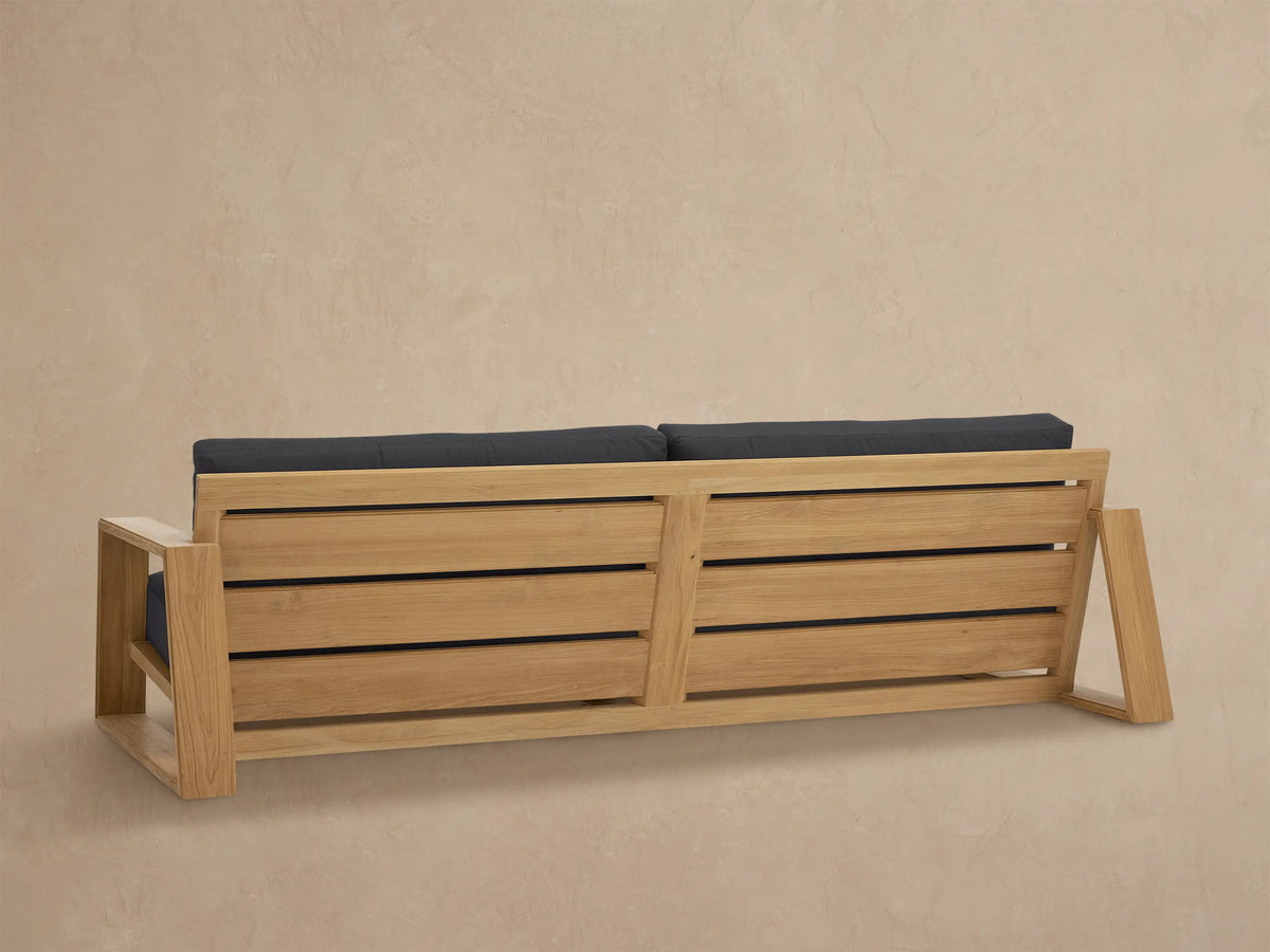 Front view of the Canyon Outdoor Teak Sofa with natural teak frame and dark grey cushions.