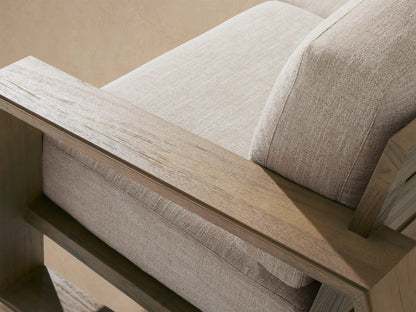 Close-up of the natural teak armrest and beige textured cushions of the Canyon Outdoor Teak Sofa.