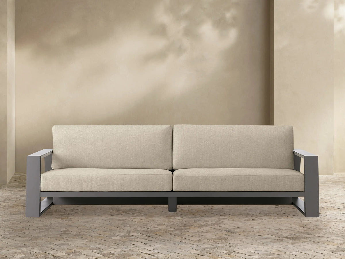 Canyon Outdoor Aluminum Sofa with a dark gray powder-coated frame and light beige InsideOut Performance Fabric cushions, front view.