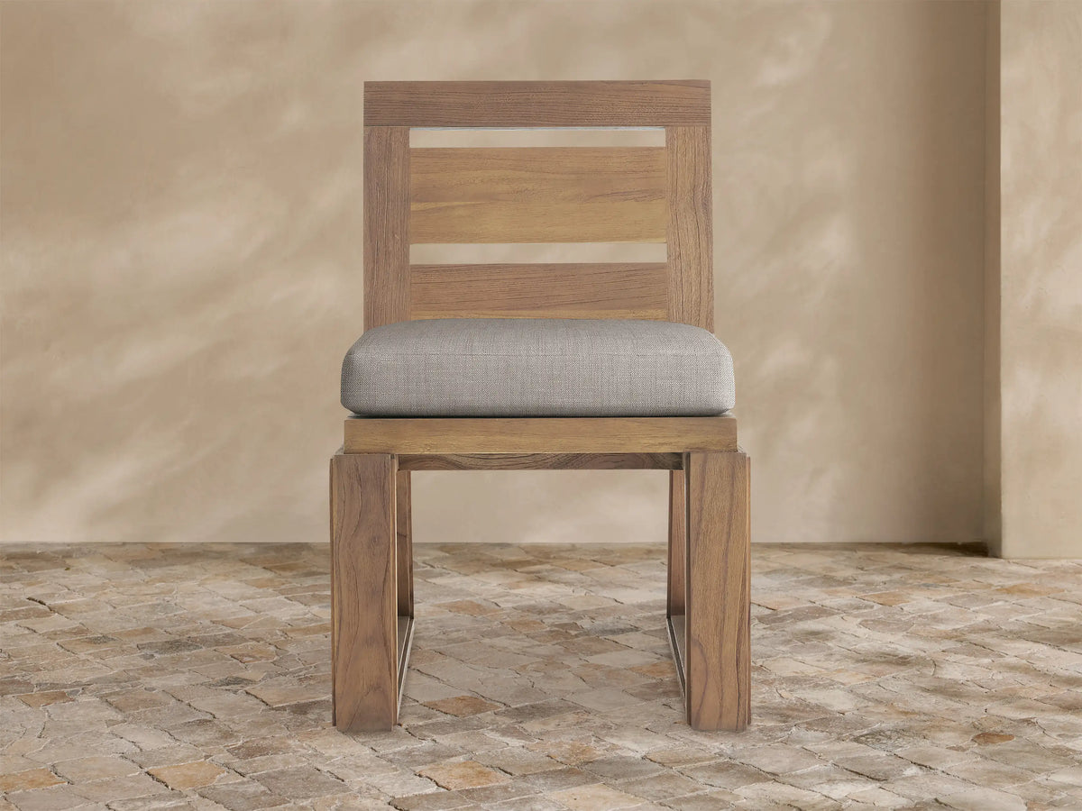 Front view of Canyon Outdoor Teak Dining Side Chair, natural brown wood, slatted back, light grey cushion, U-shaped base.
