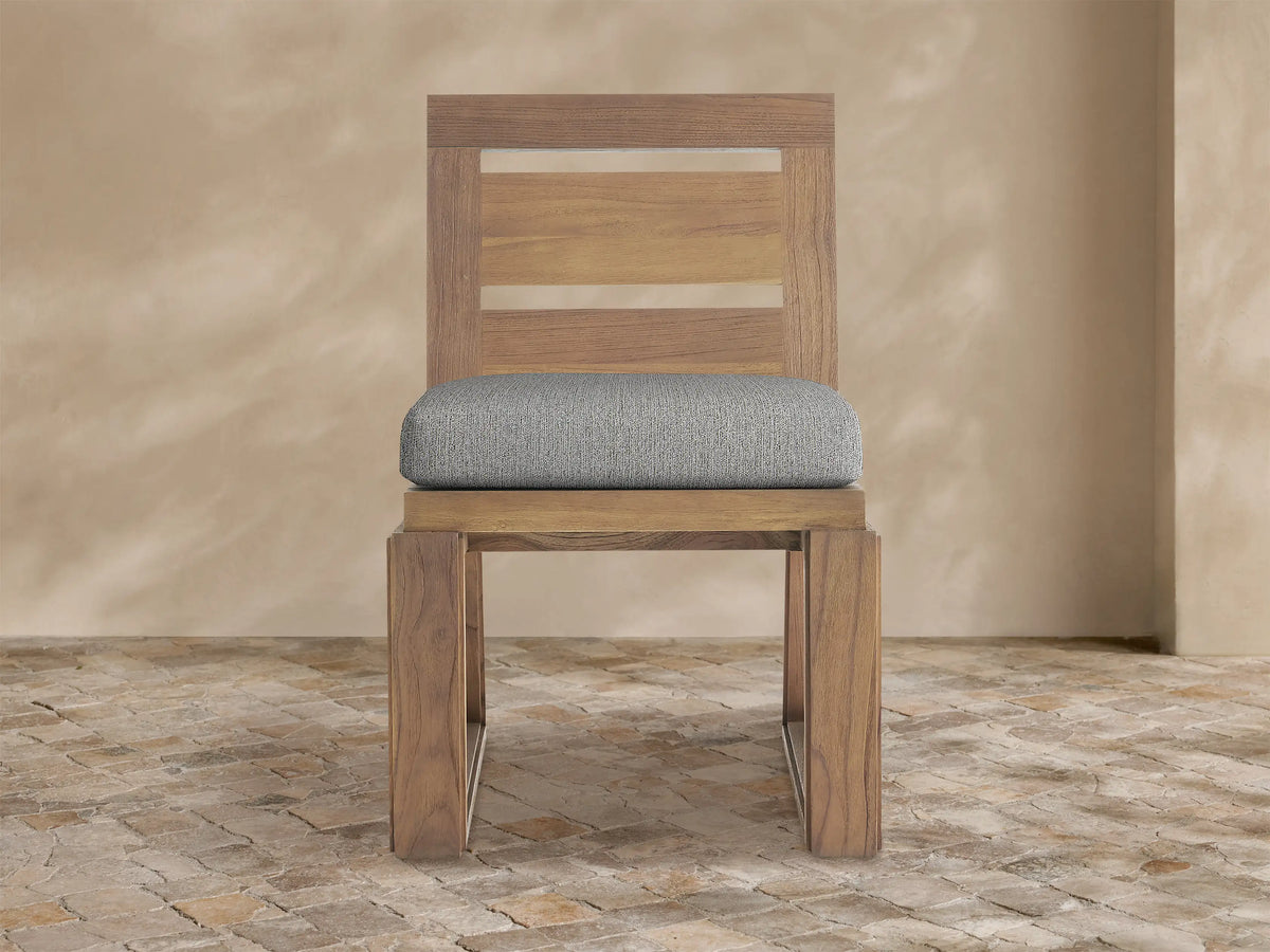 Canyon Outdoor Teak Dining Side Chair, front view. Teak wood frame, slatted back, light gray seat cushion on white background.