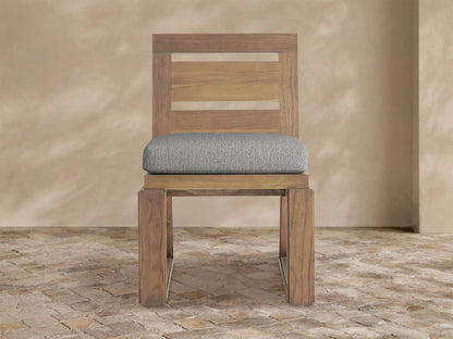 Canyon Outdoor Teak Dining Side Chair, front view. Teak wood frame, slatted back, light gray seat cushion on white background.