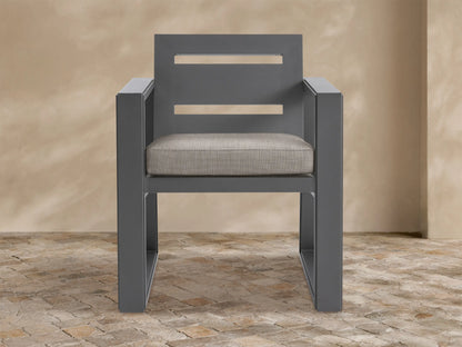 Front view of Canyon Outdoor Aluminum Dining Arm Chair, dark gray frame with two horizontal cutouts on back, light beige cushion.