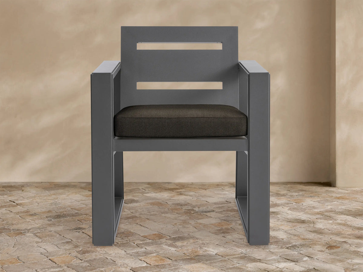 Front view of the Canyon Outdoor Aluminum Dining Arm Chair with a dark gray frame and two horizontal cutouts in the backrest, featuring a dark brown seat cushion.
