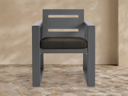 Front view of the Canyon Outdoor Aluminum Dining Arm Chair with a dark gray frame and two horizontal cutouts in the backrest, featuring a dark brown seat cushion.
