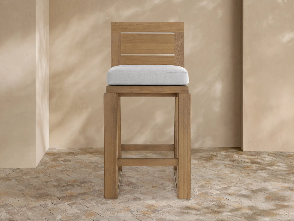 Canyon Outdoor Teak Barstool, front view, light brown teak wood frame with a light gray cushion and two-slat backrest.