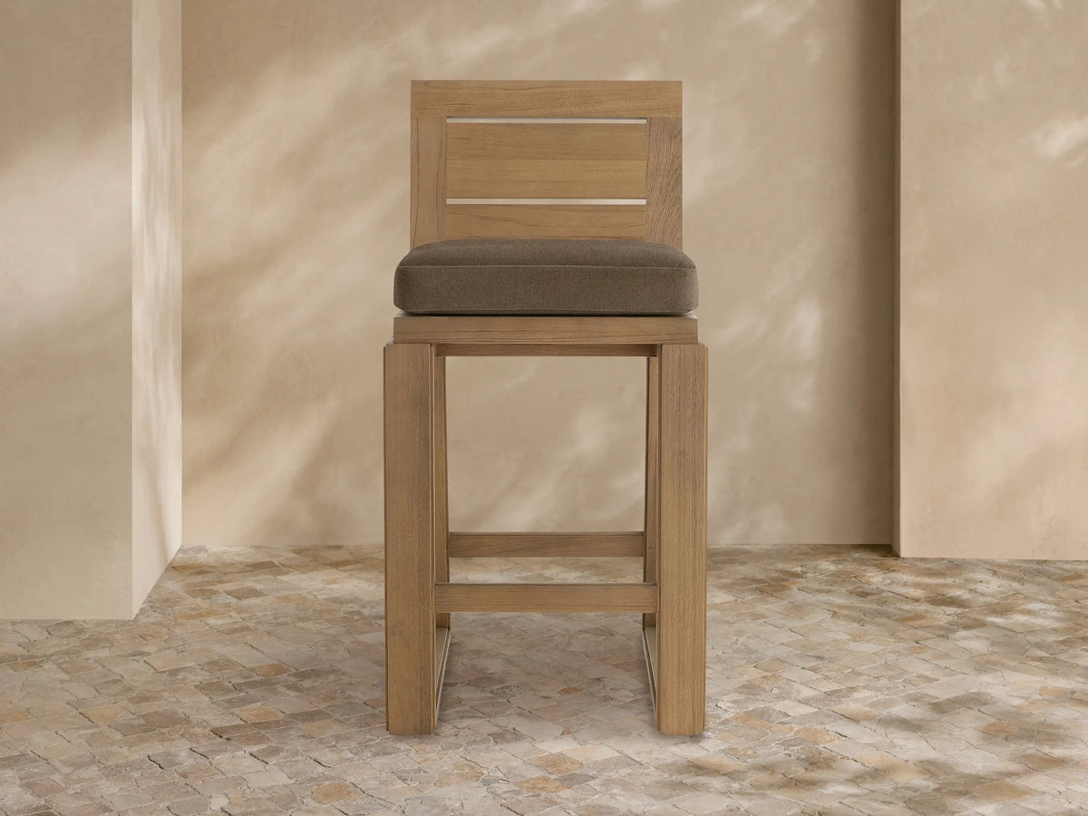 Canyon Outdoor Teak Barstool, front view. Natural teak wood frame with slatted backrest & plush dark brown cushion.