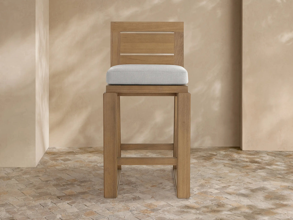 Canyon Outdoor Teak Barstool, front view. Natural teak wood frame with slatted backrest & light grey seat cushion.
