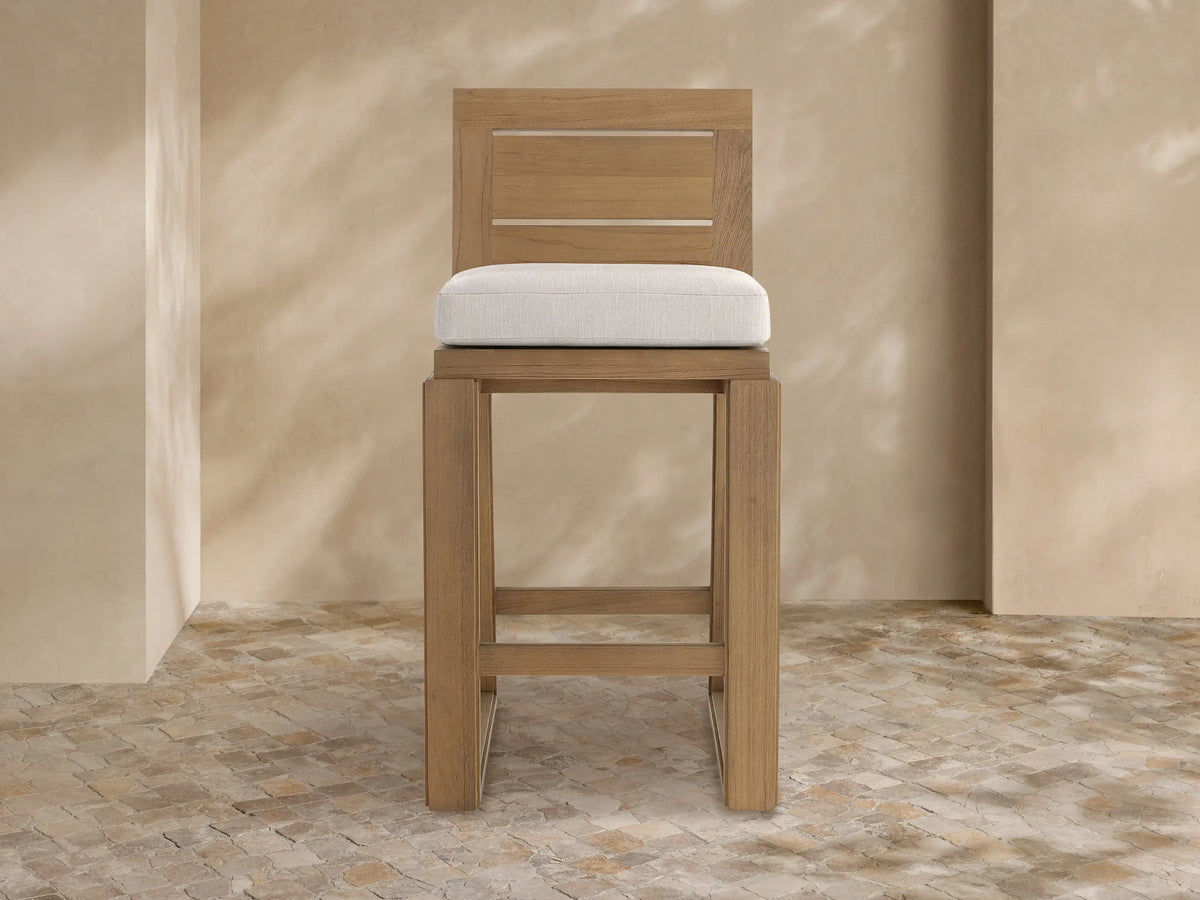 Canyon Outdoor Teak Barstool, light brown teak wood with slatted backrest and light beige upholstered seat cushion, front view.