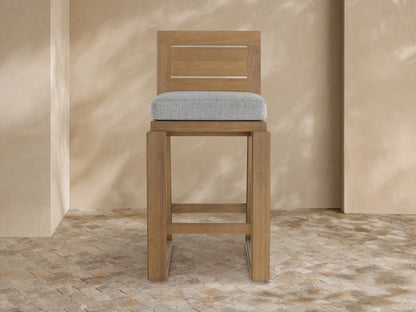 Canyon Outdoor Teak Barstool, front view, natural wood finish with a gray upholstered seat cushion and slatted backrest.