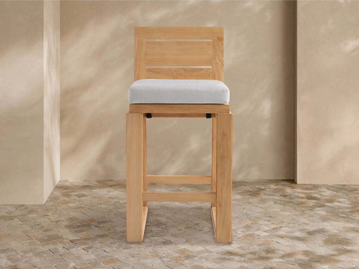 Canyon Outdoor Teak Barstool with light brown wood frame, slatted backrest, and light gray cushion, shown front view.