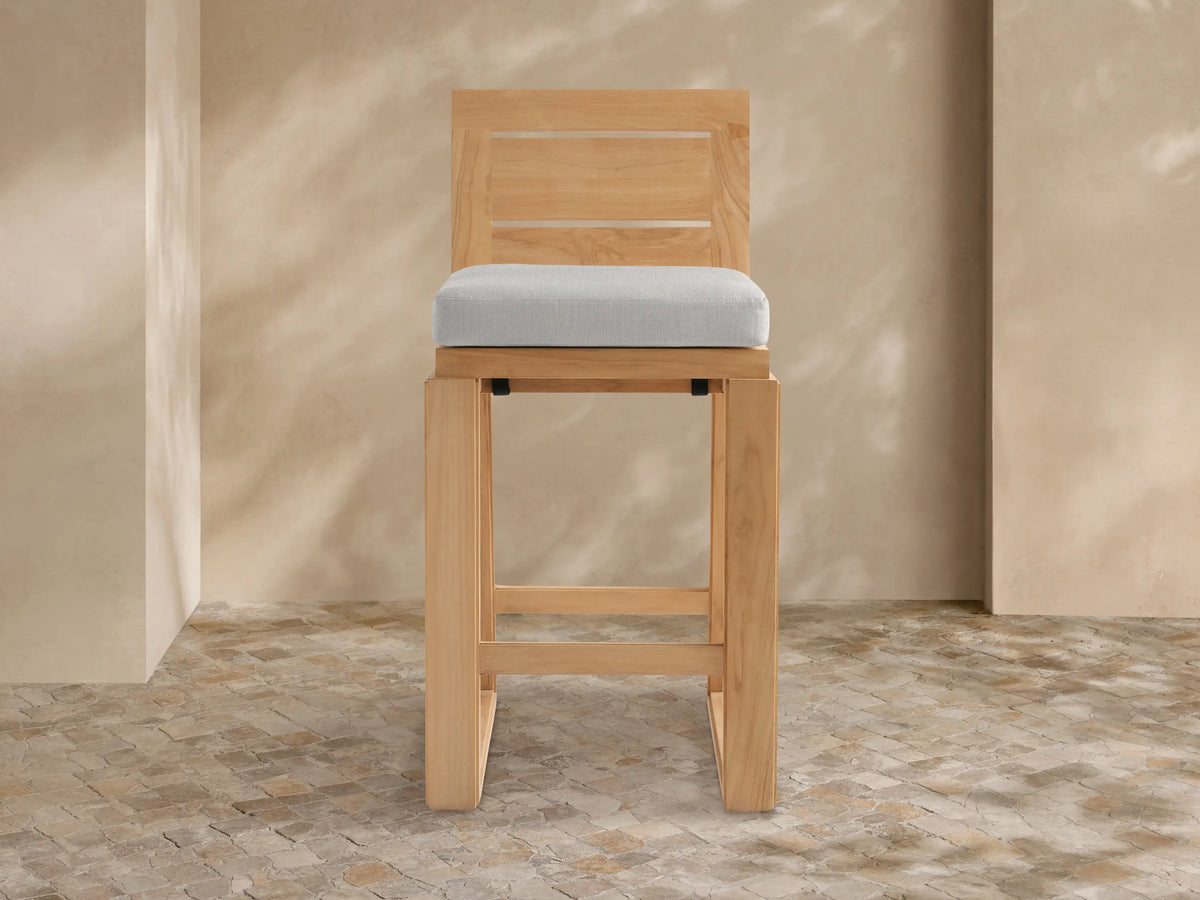 Front view of Canyon Outdoor Teak Barstool with light brown teak slatted back, light grey cushion, and rectangular teak frame.
