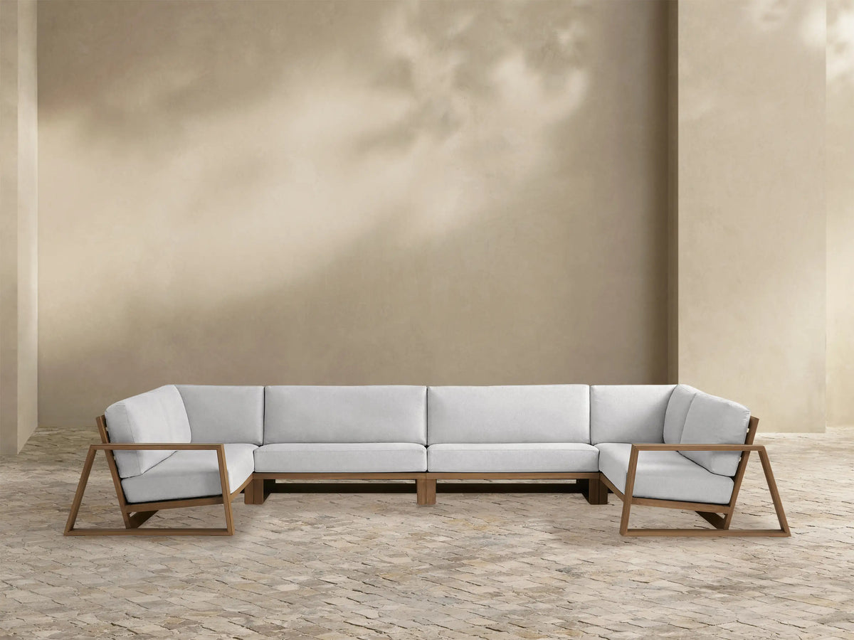 Canyon Outdoor Teak Four-Piece Sectional. U-shaped, light natural teak wood frame with open arms, and off-white cushions.