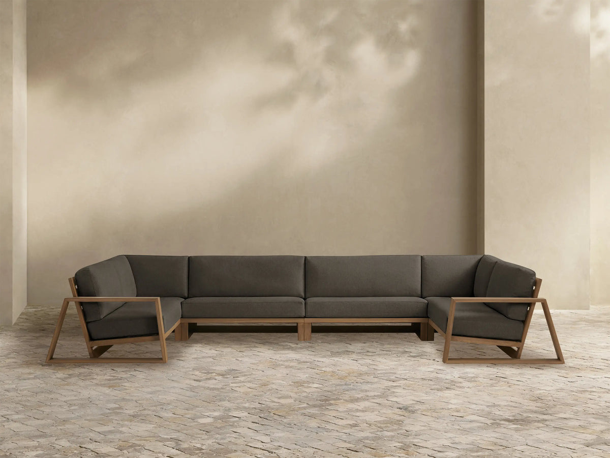 Canyon Teak Sectional, L-shaped, dark gray cushions, modern open geometric teak wood frame, front view on white background.
