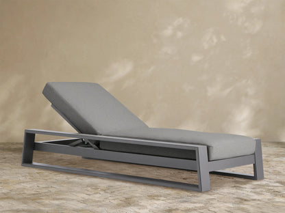 Canyon Outdoor Aluminum Chaise. Dark gray aluminum frame, light gray cushioned seat, adjustable backrest angled up on white.