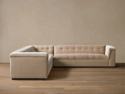 L-shaped Cameran Three-Piece Sectional sofa in light beige, with square-tufted backrests, on a wooden floor against a beige wall.