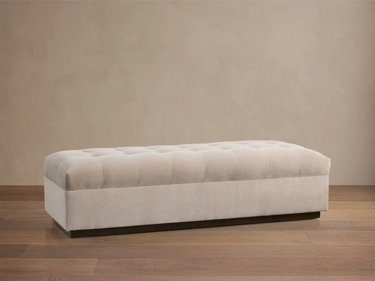 Cameran Bench in a soft beige fabric, featuring tufted detailing on the seat, set against a neutral wall and wooden floor.