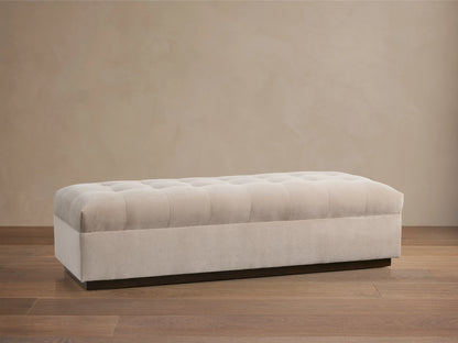 Light beige upholstered Cameran Bench, rectangular with a tufted top and dark recessed base, shown on a wooden floor.