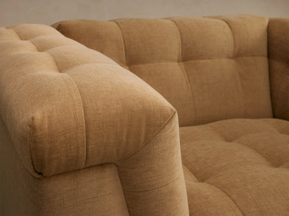 Cameran Chair in warm beige fabric, tufted design, plush armrests, and cushioned backrest, on wooden floor, neutral background.