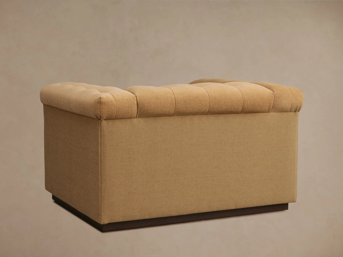 Cameran Chair in brown fabric, featuring a padded backrest and armrest with visible tufting, showcasing a close-up angle.