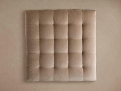 The Cameran Ottoman features a light beige, tufted top with soft fabric, and a rectangular shape on a dark wood base, set on wooden flooring.