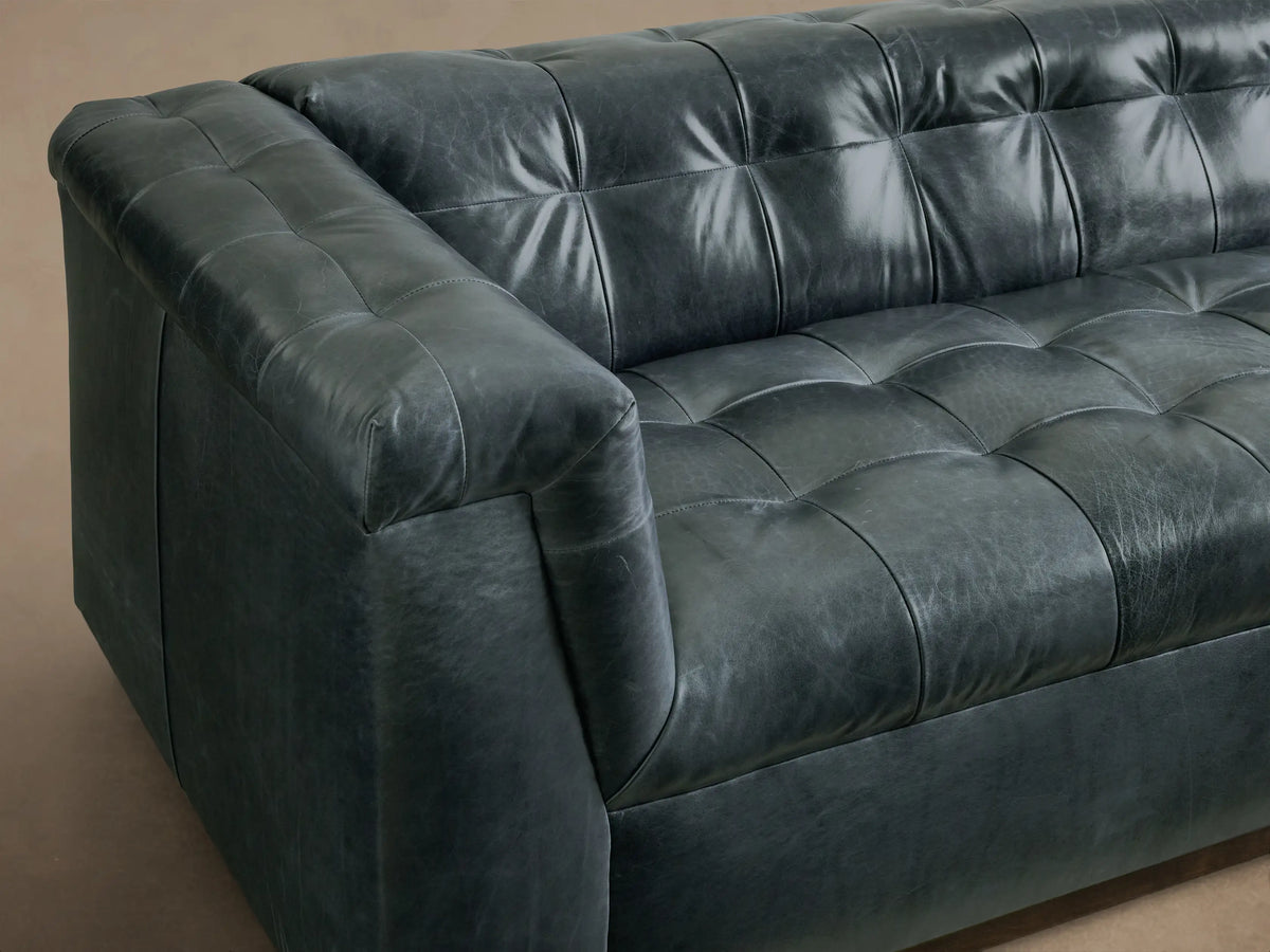 Side view of the charcoal Cameran Leather Sofa, featuring tufted back and seat cushions with a rolled armrest.